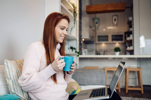 istock Cute redhead girl using laptop at home 1354212459