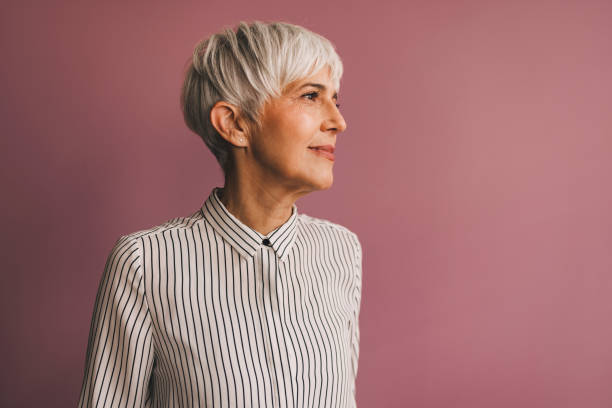 retrato de una mujer de negocios senior - vertical studio shot indoors pink fotografías e imágenes de stock