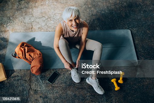 istock Senior Woman Tying Laces on her Sneakers Before Home Workout 1354213615