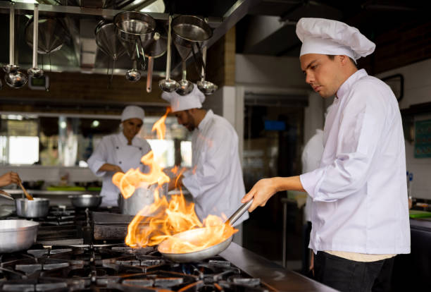istock Chef cooking in a commercial kitchen and sauteing vegetables in a pan 1354214269
