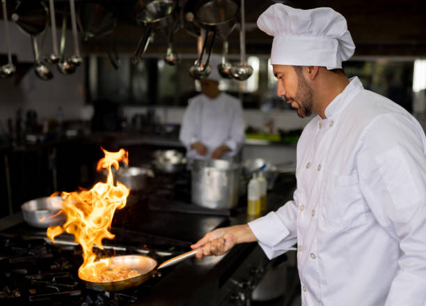 istock Chef cooking at a restaurant and flaming vegetables in a pan 1354214285