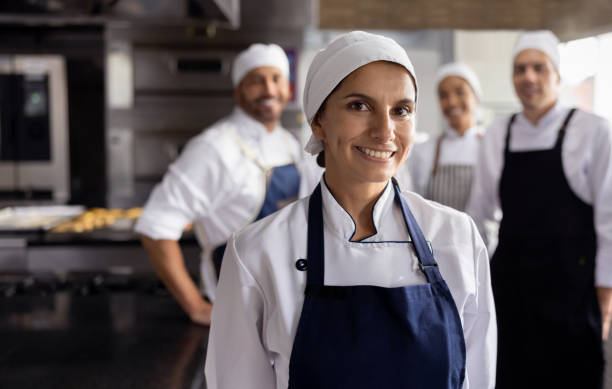 istock Happy female baker working at a bakery with her team 1354214295