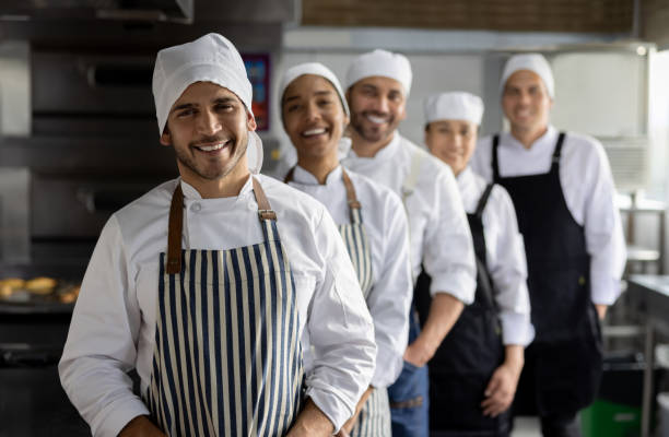 istock Happy group of bakers in a row while working at the bakery 1354214298