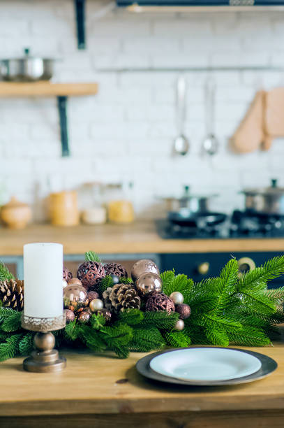 istock Empty plates on wooden table close-up. Decorated Christmas tree in kitchen. Table setting on New Years in interior... 1354214452