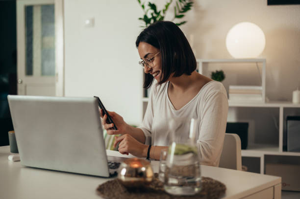 istock Woman using smartphone and a laptop for an online meeting while working from home 1354214551