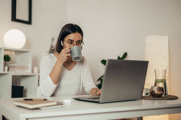 istock Woman drinking coffee and using a laptop while working from home 1354218041