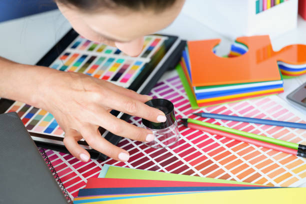istock Girl designer looking through magnifying glass at colour palette 1354219040
