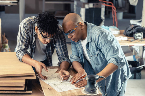 Two black man factory worker examining blueprint and checking a list of daily assignment.Preparing for working day. stock photo