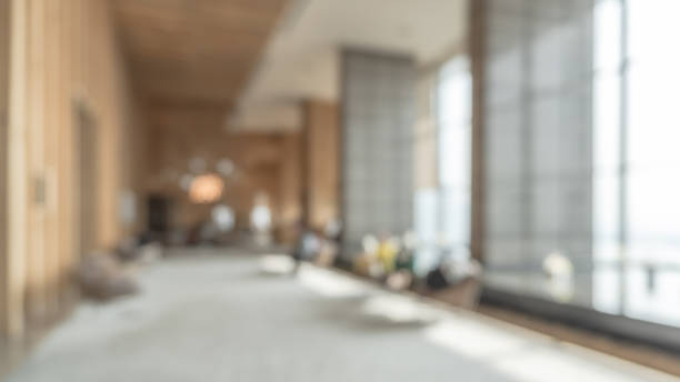 Blurred hotel or office building lobby blur background interior view toward reception hall, modern luxury white room space with blurry corridor and building glass wall window