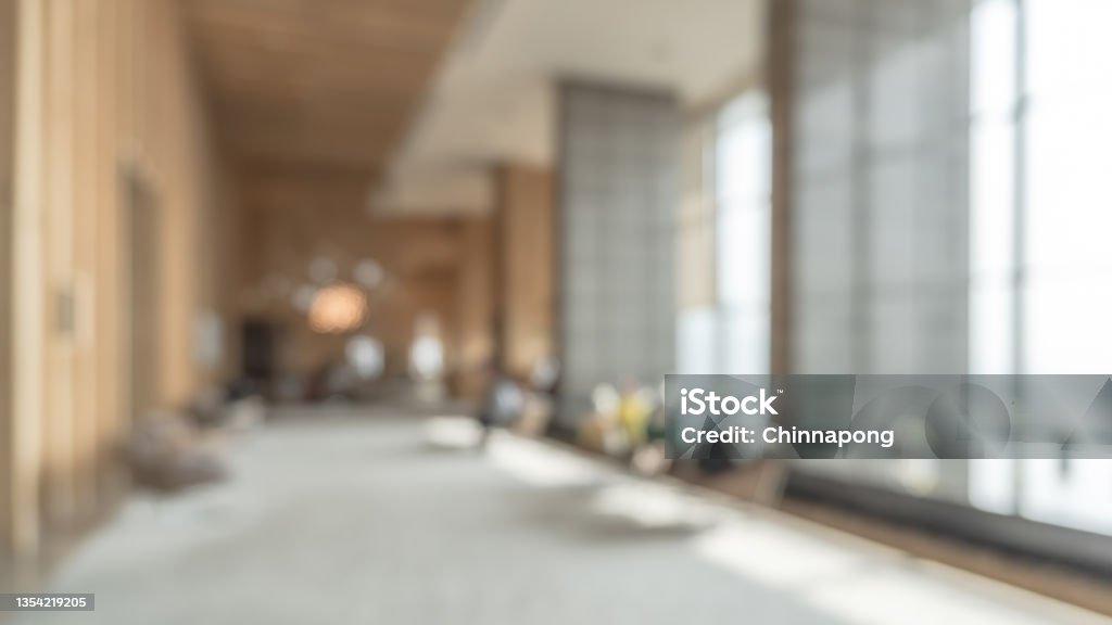 Blurred hotel or office building lobby blur background interior view toward reception hall, modern luxury white room space with blurry corridor and building glass wall window Office Stock Photo