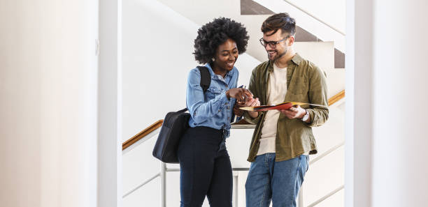 Two students standing in college lobby and talking. stock photo