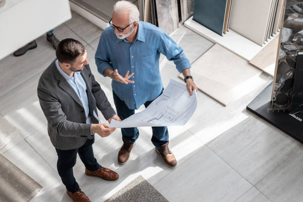 Two architects looking at the blueprint and discuss about business strategy. Two architects looking at the blueprint and discuss about business strategy. architect stock pictures, royalty-free photos & images