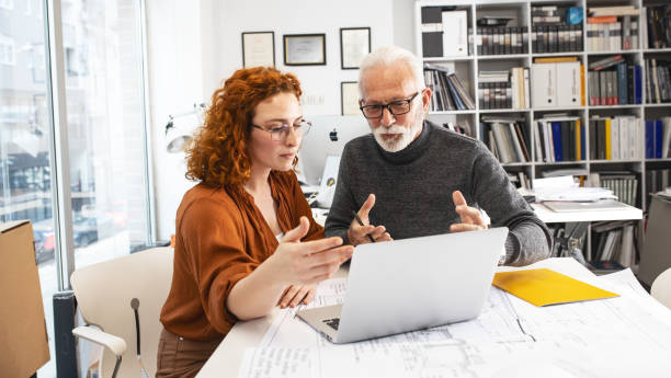istock Senior designer hels his young female coworker to solve problem.Design studio. 1354222862