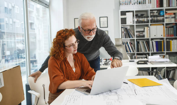 istock Senior designer hels his young female coworker to solve problem.Design studio. 1354222866