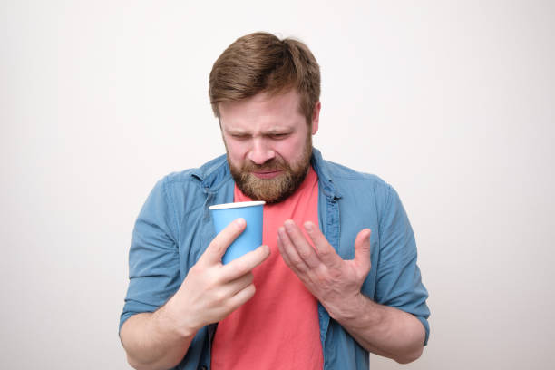 Caucasian man with a paper cup in his hand feels shock and disgust, he drank the tainted drink. White background. Caucasian man with a paper cup in his hand feels shock and disgust, he drank the tainted drink. Studio, white background. gross coffee stock pictures, royalty-free photos & images