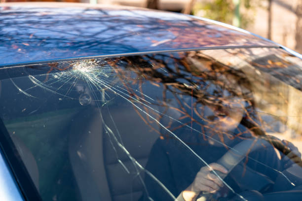 Shocked woman in car with broken windshield  and cracks. Car accident. Selective focus stock photo