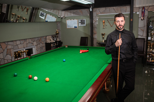 Portrait of professional snooker player next to snooker table