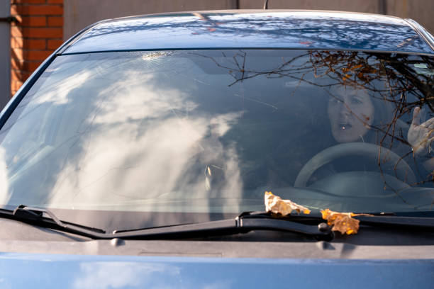 Shocked woman in car with broken windshield  and cracks. Car accident. Selective focus stock photo