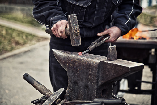 Close up of hand working with hammer on an anvil. Blacksmith in work.