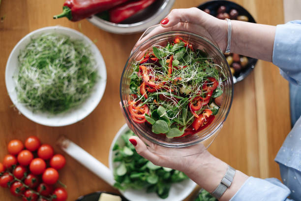 istock Woman hands hold a bowl with salad on veggies background 1354226875