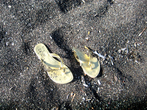 goldsandale am perissa beach, santorini, griechenland. - black sand beach santorini greece stock-fotos und bilder