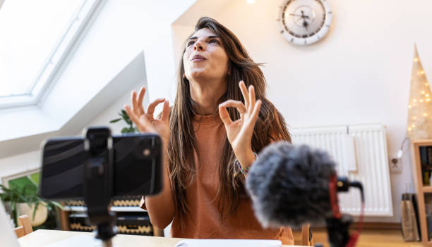istock Young female vlogger recording video for her video channel. 1354230204