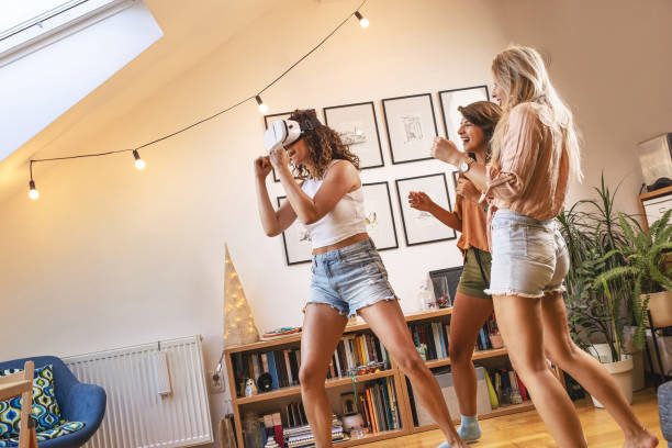 istock Female friends using virtual reality device at home. They laughing and making fun. 1354230271