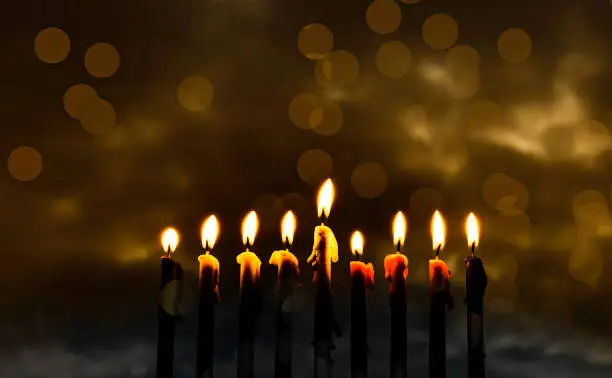 Menorah and burning wax candles as symbol of Hanukkah - Jewish Holiday of Miracle Light. Blurred background of overcast sky, digitally generated bokeh on night sky