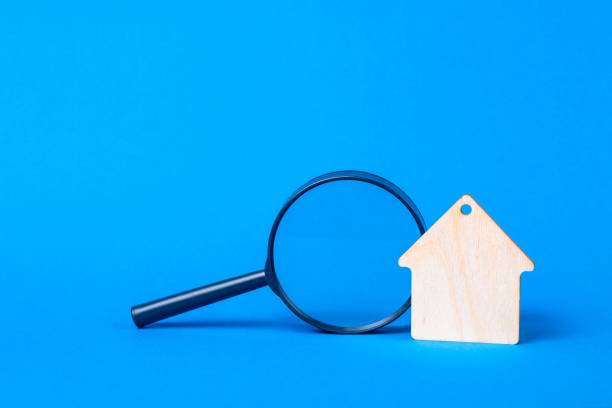 istock Keychain Wooden house and magnifier on a blue background. 1354232403
