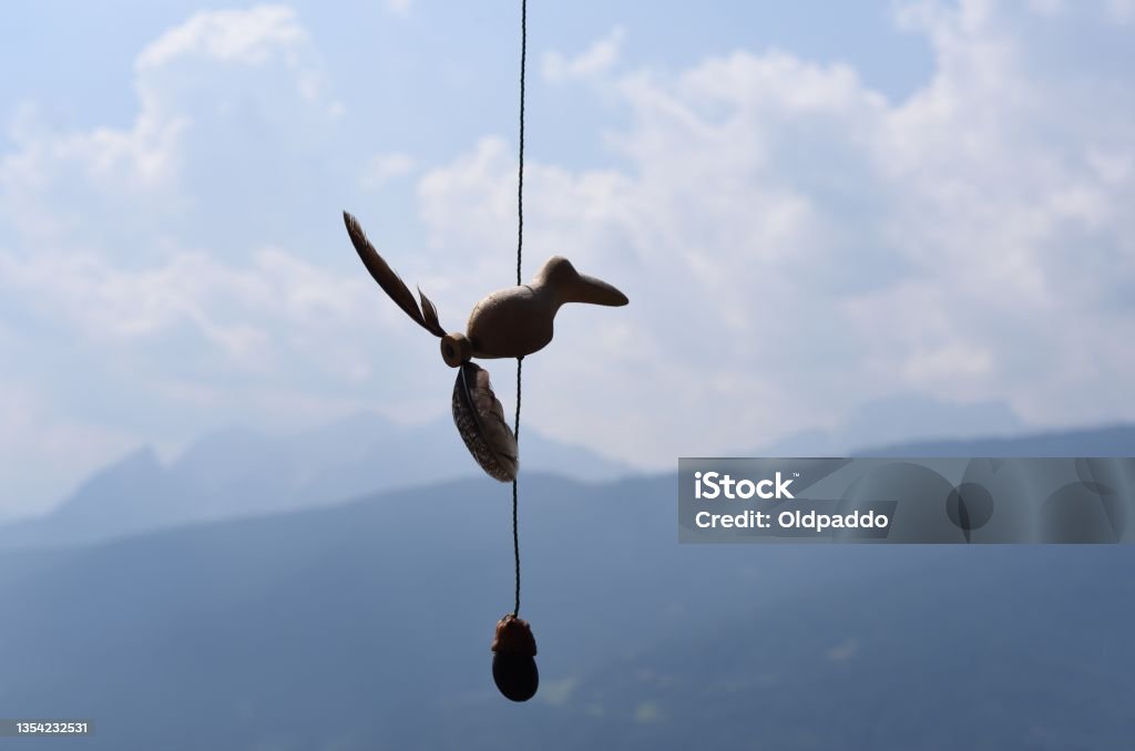 Wooden toy A small wooden toy hung to challenge the wind against the backdrop of the mountains Bird Stock Photo