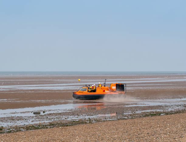 'Hunstanton Flyer', the RNLI rescue hovercraft on an exercise at Heacham H-003, the ‘Hunstanton Flyer’, an RNLI (Royal National Lifeboat Institution) rescue hovercraft leaving the shore during an exercise on the beach at Heacham in Norfolk, Eastern England. The ‘Hunstanton Flyer’, based in the town of the same name just along the coast, is one of only a few of these H-Class rescue craft, which are used in areas where sands are vast and incoming tides can have fatal consequences when unwary beach-lovers find themselves cut off on a sandbank. Being manoeuvrable in places with shallow water and on sandbanks, the ‘Flyer’ is perfect for this area of The Wash and parts of the North coast of Norfolk. amphibious vehicle stock pictures, royalty-free photos & images
