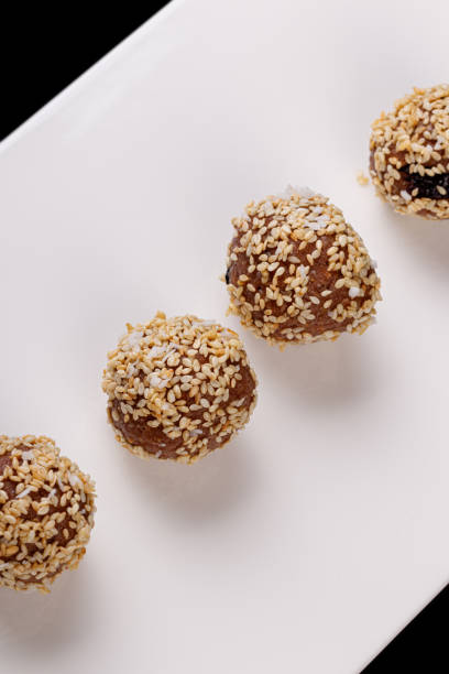 istock Beautiful candies with sesame seeds on a white plate on a black background 1354234780