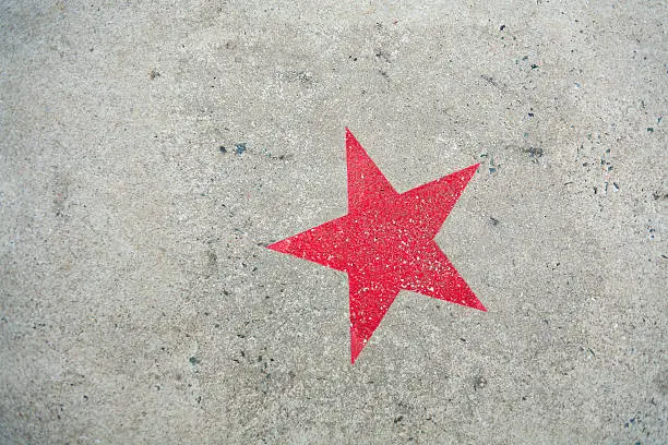 A red star stencil painted on  concrete footpath