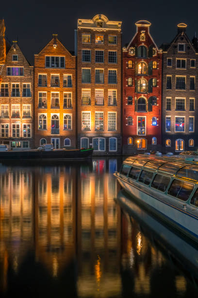 houses on water in night amsterdam and pleasure boat - amsterdam holland city night imagens e fotografias de stock