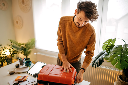 Handsome guy packing his bags for a winter vacation