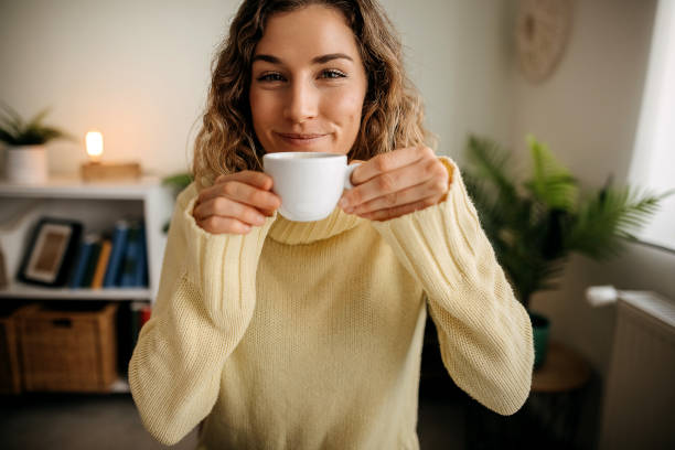 istock Laughing young woman drinking coffee while working from home 1354239408