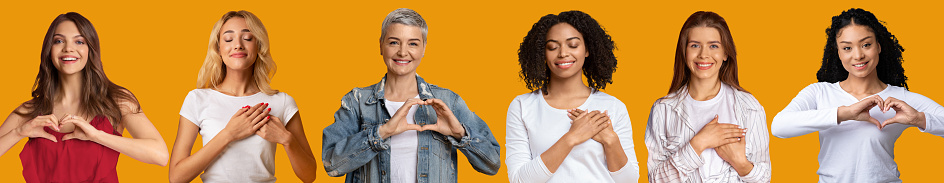 Smiling adult and young european and afro american women press hands to chest, make heart gesture, are grateful and show care sign, isolated on orange background. Positive human emotions, collage
