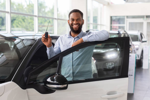 acquisto di auto. uomo nero con le chiavi in mano in piedi vicino all'auto nuova - car african descent shopping car dealership foto e immagini stock