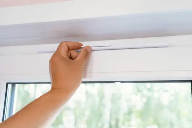 Photo of Supply ventilation on a plastic window, a man's hand moves the ventilation lever on the window