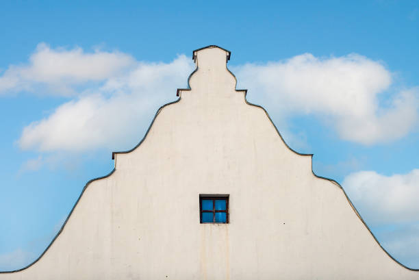 istock Old building roof and wall with blue cloudy sky in background 1354240944