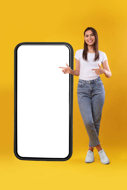 istock Woman pointing at big white empty smartphone screen, mock-up 1354241027