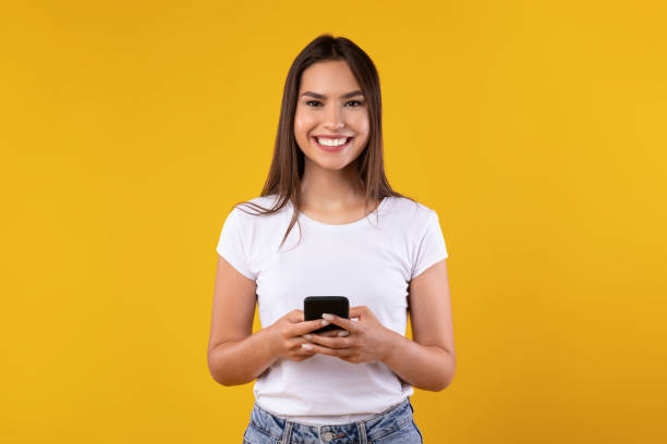 istock Happy excited lady using mobile phone at yellow studio 1354242078