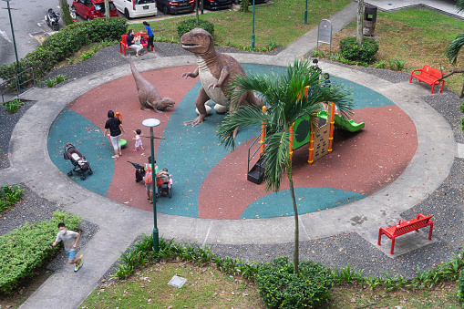 Singapore, Singapore - August 15, 2021: Children playing at a dinosaur-themed public playground in Toa Payoh.