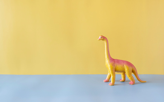 Toy Dinosaur on a saturated colorful base with lots of copy space.