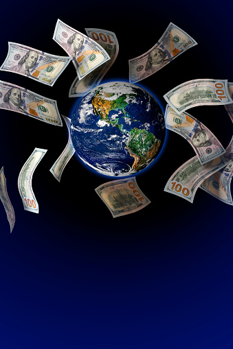 Dollar bills (US $100 banknotes) flying around the Earth globe. Dark blue background, space for copy. Earth globe image provided by NASA - https://earthobservatory.nasa.gov/images/885/earth-from-space