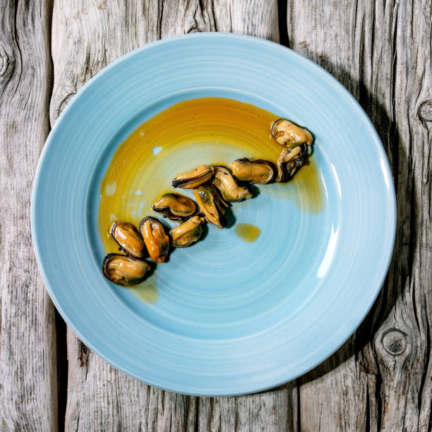 Smoked mussels in oil on blue ceramic plate