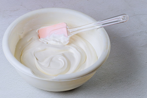 Homemade vanilla whipped cream in a bowl with spatula.
