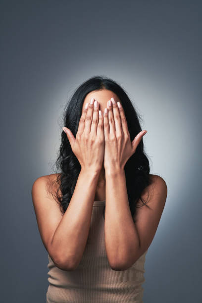 foto de una joven posando con las manos sobre la cara - avergonzamiento fotografías e imágenes de stock