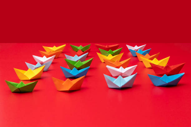istock Multicolor paper boat on the red background 1354248267