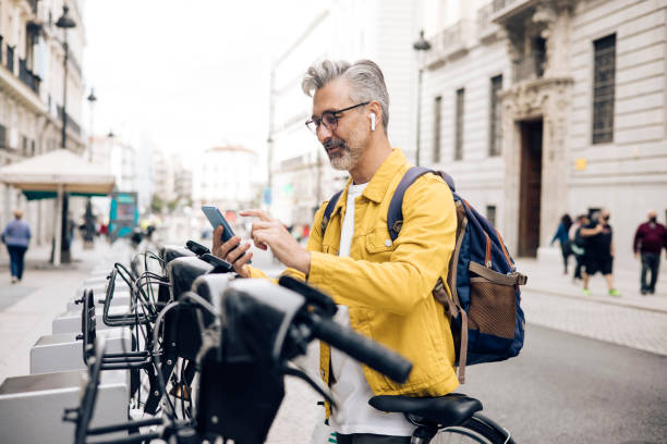 turista maduro alugando uma e-bike - bikeshare - fotografias e filmes do acervo
